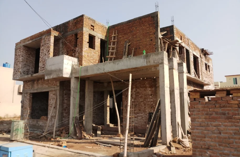 A concrete house frame nearing structure completion, showing the vertical and horizontal concrete beams and columns.