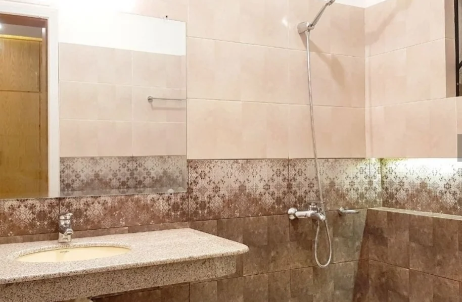 Construction site view of a bathroom showing the wall prepared for tiling, with exposed plumbing and light colored floor.