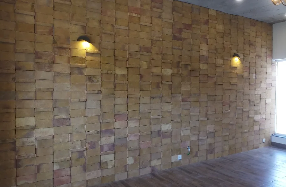 Close-up on an exterior wall section covered in horizontally stacked beige/yellow stone cladding tiles.